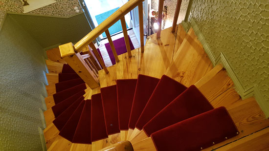 Tapete im Flur tapeziert und Stufen der Treppe mit rotem Teppichboden belegt